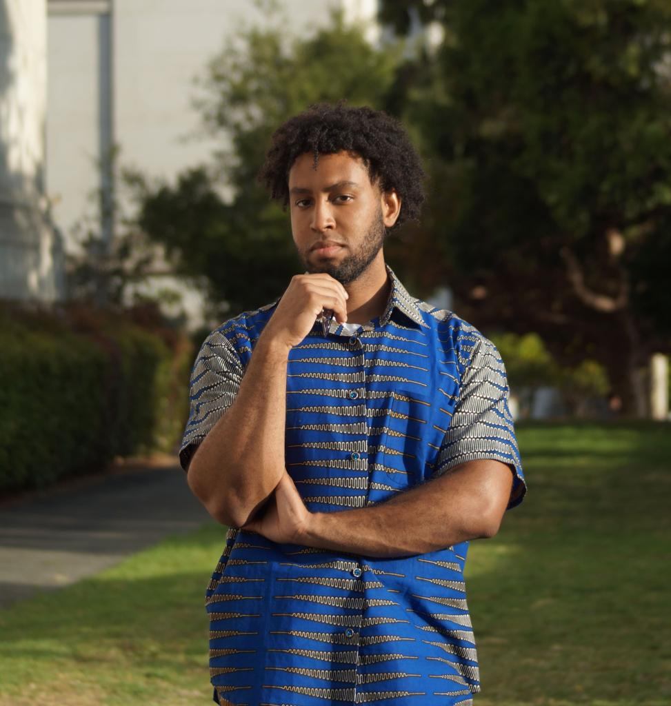 Hasan standing outside in a blue suit.